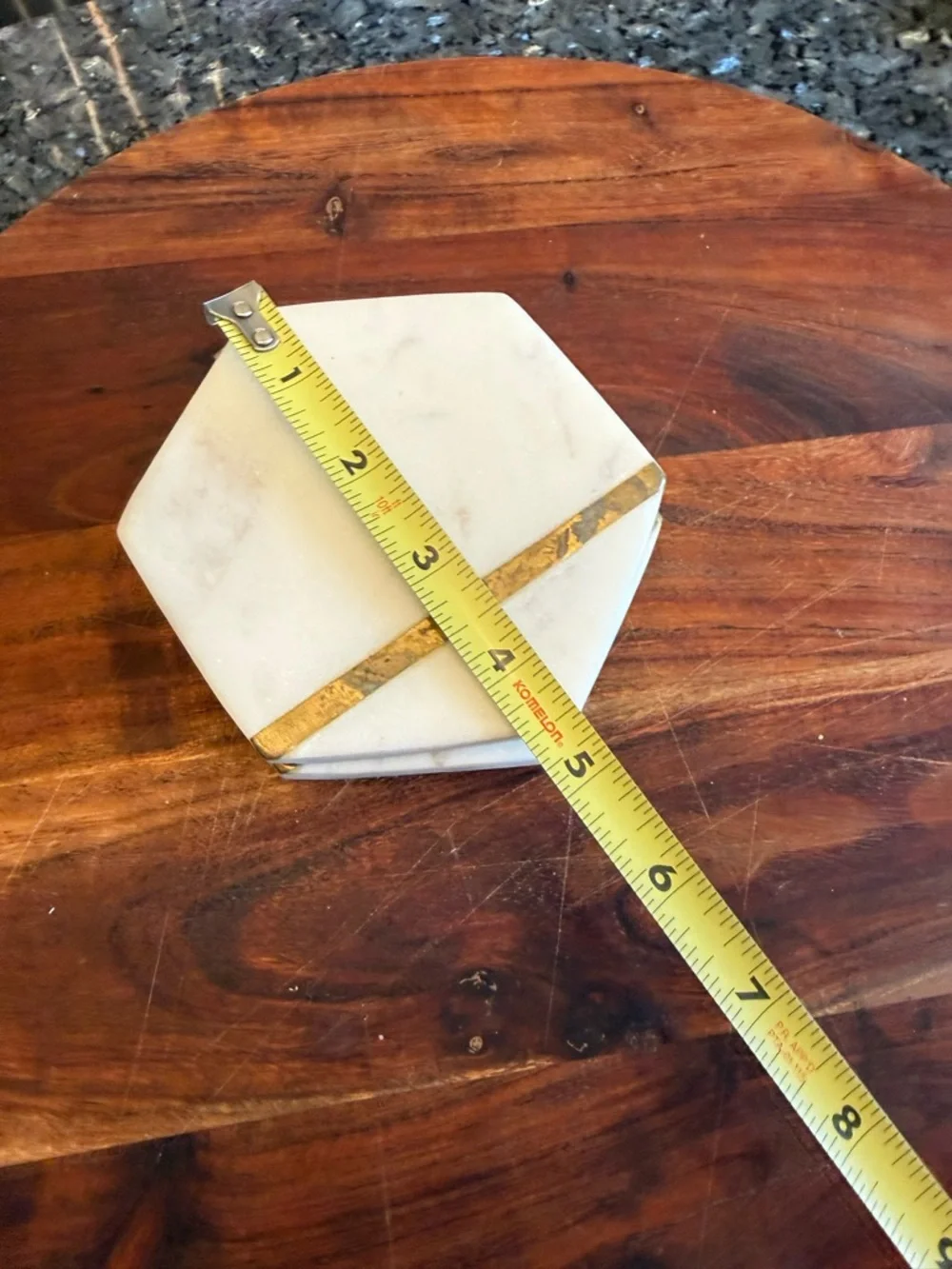 Hexagonal white marble coasters featuring a brass inlay design